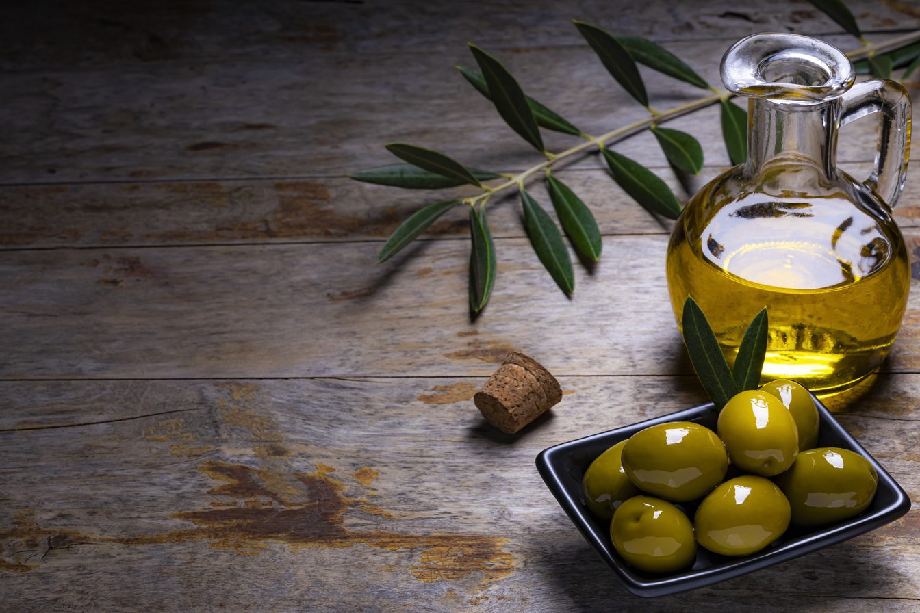 Azeite de oliva em uma colher com carboidratos ao fundo