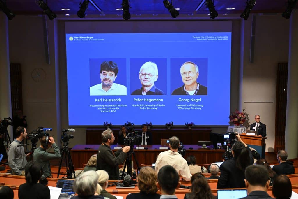 Cientistas Karl Deisseroth, Peter Hegemann e Georg Nagel recebendo o Prêmio Nobel de Medicina 2026 por suas descobertas em optogenética.